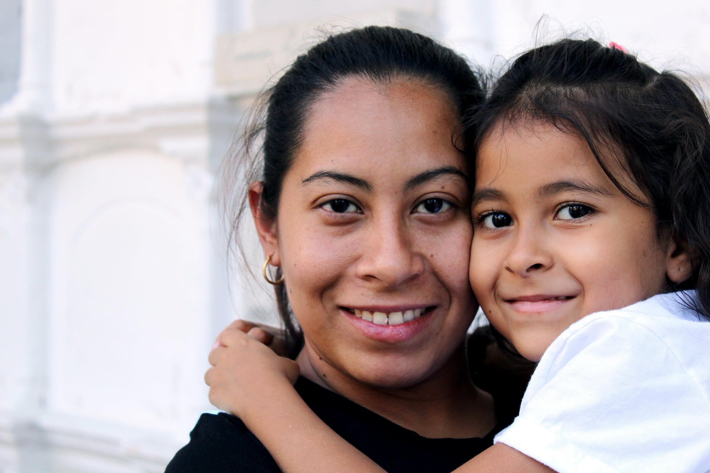 A woman holding on to a child, both smiling